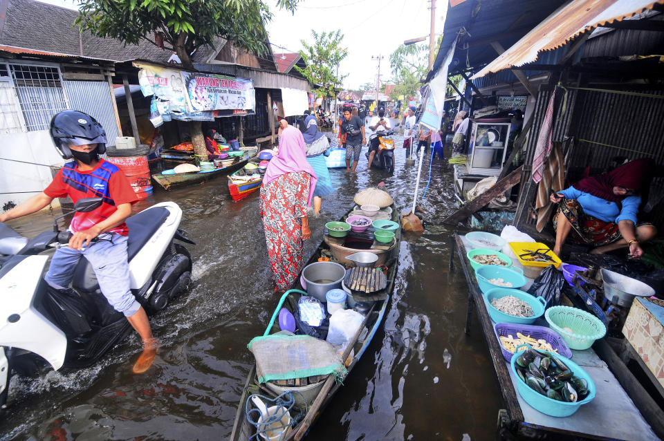 People make their way through flood water in Banjarmasin, South Kalimantan on Borneo Island, Indonesia, Sunday, Jan. 17, 2021. many thousands of people have been evacuated and a number have been killed in recent days in flooding on Indonesia's Borneo island, officials said Sunday. (AP Photo/Iman Satria)