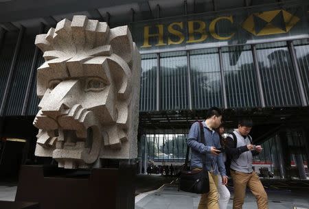 People count banknotes as they walk past a newly installed lion sculpture outside HSBC headquarters in Hong Kong March 3, 2015. REUTERS/Bobby Yip