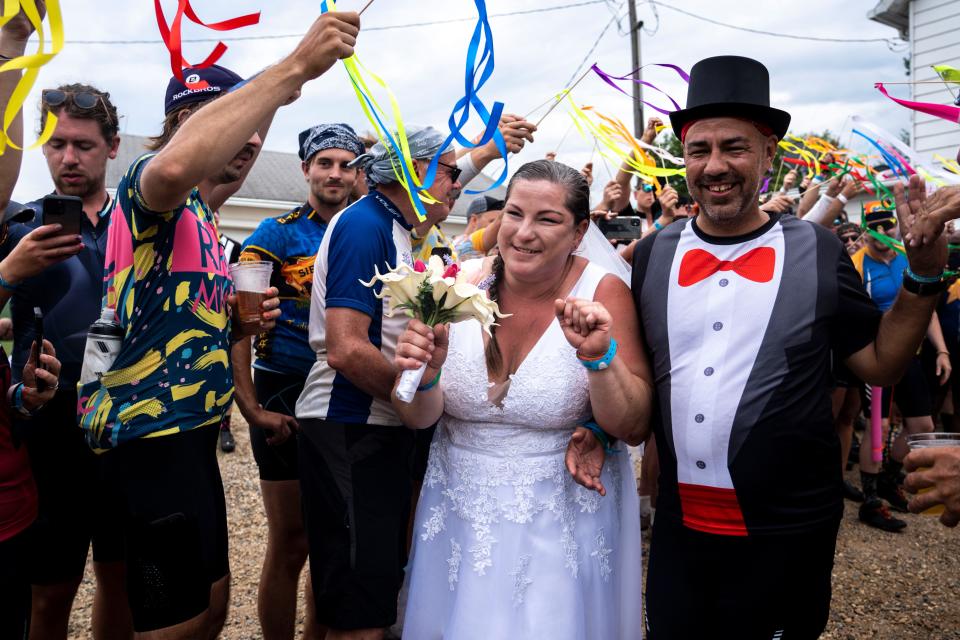 RAGBRAI riders Jamie and Joe Stacey walk hand-in-hand after their wedding at the Iowa Craft Beer Tent on Tuesday, July 25, 2023, near Luther.