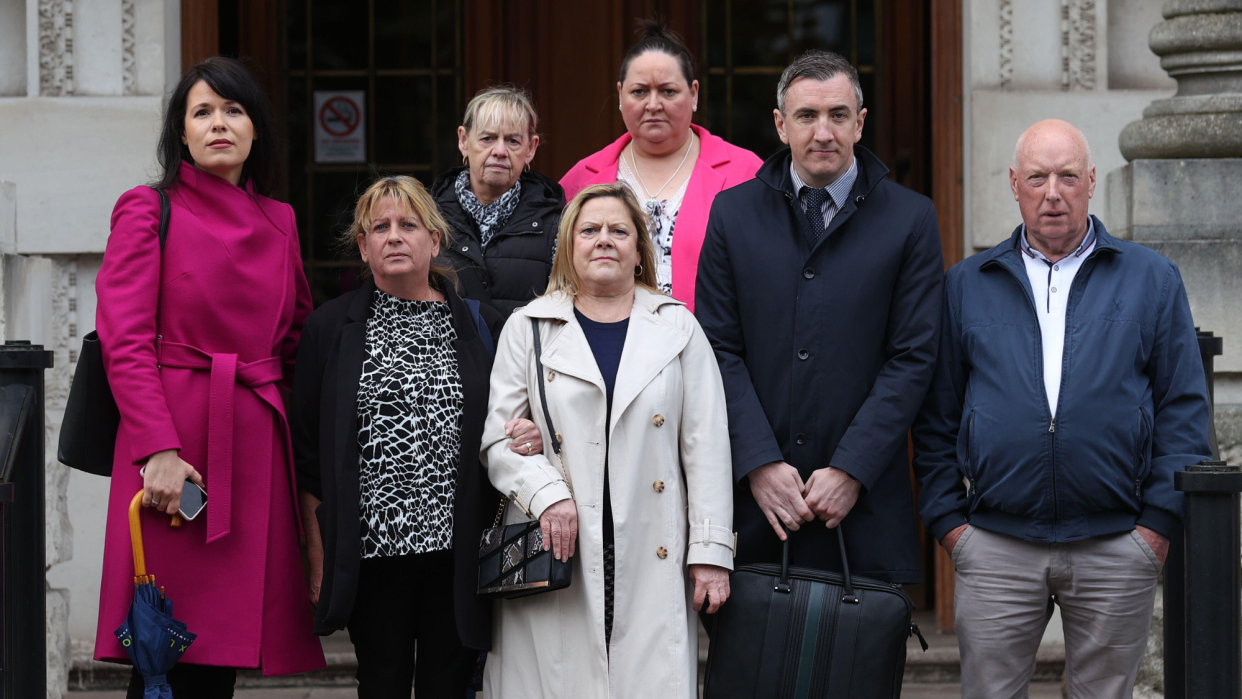  Relatives of people killed during the Troubles stand outside Belfast's High Court . 