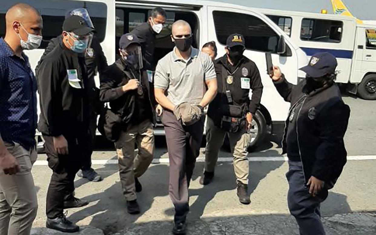 Joseph Scott Pemberton is escorted by immigration officers and US personnel as he arrives at the airport in Manila - AFP