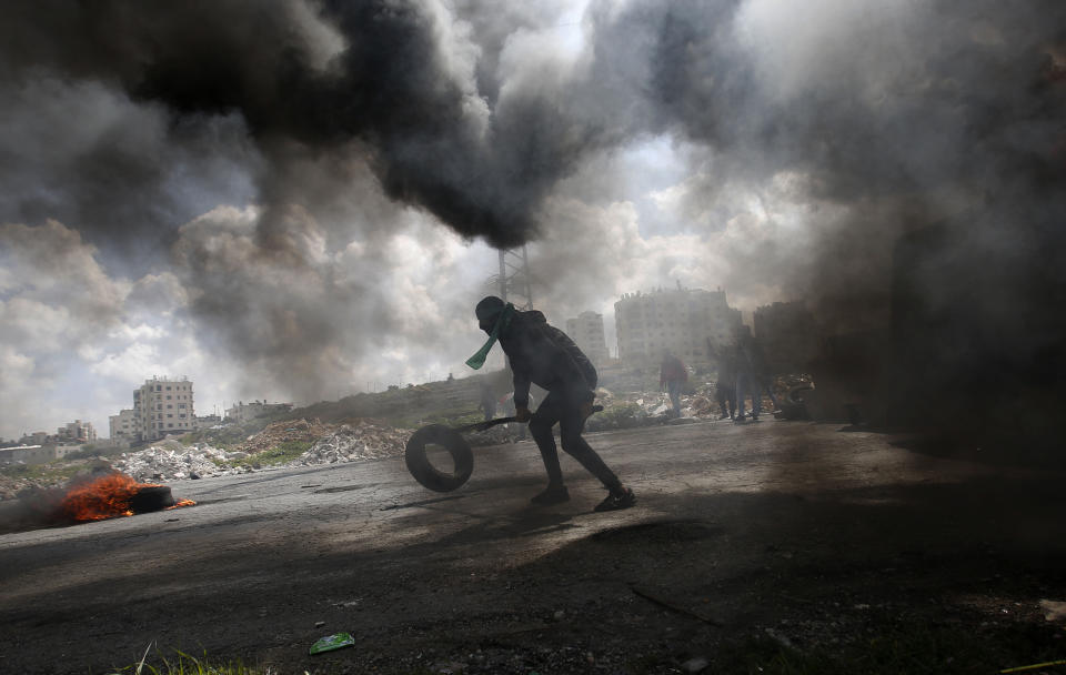 A Palestinian protester burns a tyre during a clashes with Israeli troops during demonstration in support of Palestinian prisoners held in Israeli jails at checkpoint Bet El near the West Bank city of Ramallah , Wednesday, March 27, 2019.(AP Photo/Majdi Mohammed)