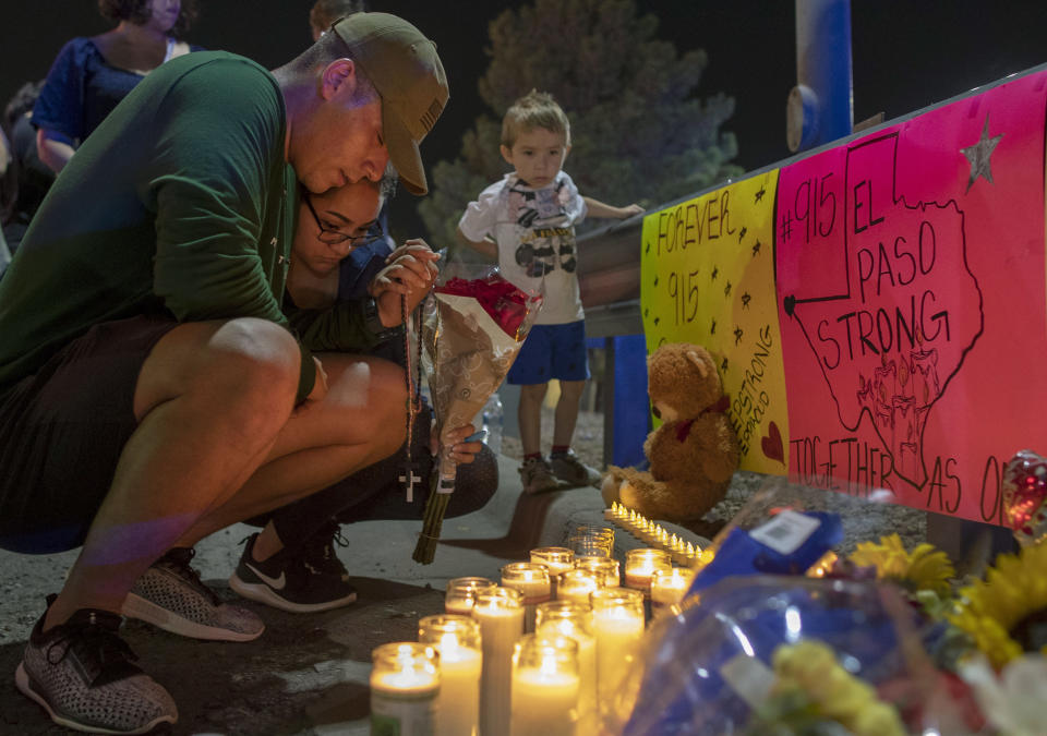 Rene Aguilar and Jackie Flores pray at a makeshift memorial for the victims of Saturday's mass shooting at a shopping complex in El Paso, Texas, Sunday, Aug. 4, 2019. (AP Photo/Andres Leighton)