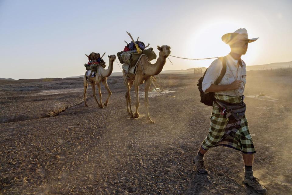 In this photo taken Monday, Jan. 28, 2013 and released by the National Geographic Society on Wednesday, Nov. 20, 2013, journalist Paul Salopek walks across the Afar desert of Ethiopia as part of his planned seven-year global trek from Africa to Tierra del Fuego. In Paul Salopek's first year of his trek across the globe, the reporter walked alongside his camels for days in Ethiopia without seeing glass or bricks or any other signs of modern humanity, ate a hamburger on a U.S. military base, was shadowed by minders in the Saudi desert – and now has only 20,000 miles (32,000 kilometers) to go. (AP Photo/National Geographic Society, John Stanmeyer) NO SALES, ONE-TIME USE ONLY, NO ARCHIVING