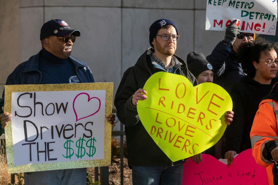 Schetrone Collier, left, a bus driver for 34 years, holds a sign next to Joel Batterman of Detroit during a rally for better bus service in front of the Spirit of Detroit statue outside the Coleman A. Young Municipal Center in Detroit on Feb. 14, 2023.