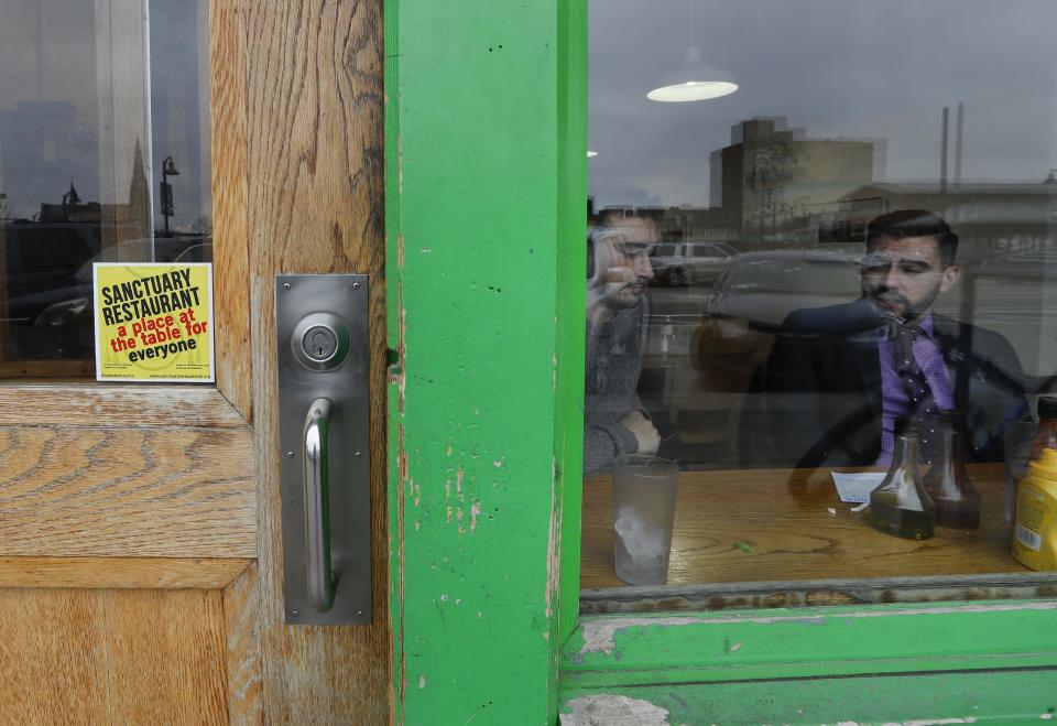 In this Wednesday, Jan. 18, 2017 photo, a sanctuary restaurant sign is shown on the door of the Russell Street Deli in Detroit. Dozens of restaurants are seeking “sanctuary” status, a designation owners hope will help protect employees in an immigrant-heavy industry and tone down fiery rhetoric sparked by the presidential campaign. (AP Photo/Paul Sancya)