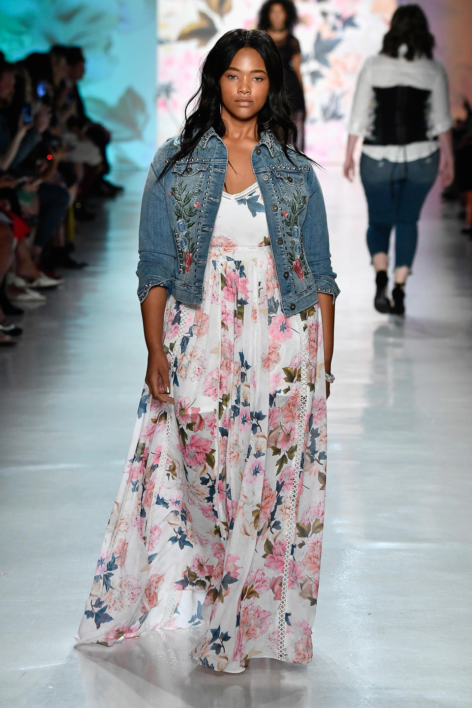 A model in an embroidered denim jacket and a floral dress at the Torrid show during NYFW. 