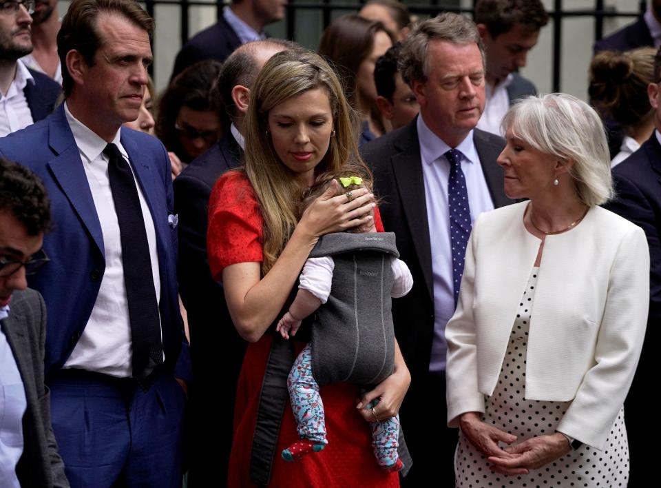 Carrie Johnson, wife of Britain's Prime Minister Boris Johnson, carries their daughter Romy next to Britain's Culture Secretary Nadine Dorries (R), Britain's Conservative party chairman Ben Elliot (L) and Britain's Scotland Secretary Alister Jack (back R) ahead of a statement by the premier in front of 10 Downing Street in central London on July 7, 2022. - Johnson quit as Conservative party leader, after three tumultuous years in charge marked by Brexit, Covid and mounting scandals. (Photo by Niklas HALLE'N / AFP) (Photo by NIKLAS HALLE'N/AFP via Getty Images)