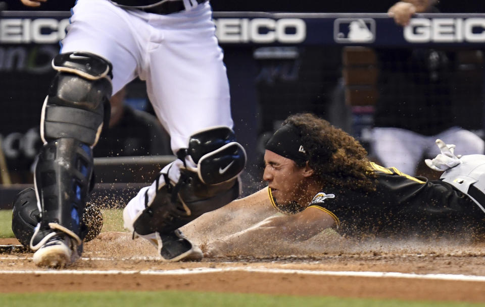 Pittsburgh Pirates' Cole Tucker dives safely into home plate as Miami Marlins catcher Alex Jackson waits for the ball during the second inning of a baseball game, Sunday, September 19, 2021, in Miami. (AP Photo/Jim Rassol)