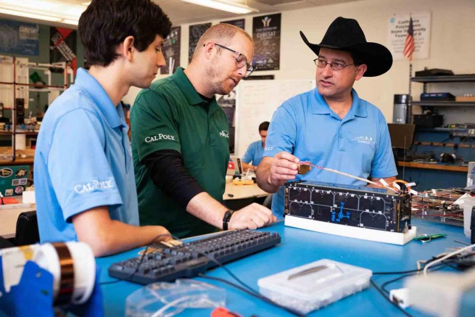 Cal Poly Professor John Bellardo, far right, measures a 3U satellite in the Cal Poly CubeSat Lab assisted by, from left Jordan Ticktin, a Cal Poly alumnus who works at NASA’s Jet Propulsion Lab, and Ryan Luke, an electrical engineering student from Santa Maria. Cal Poly students have designed and built 12 CubeSats that were launched into space.