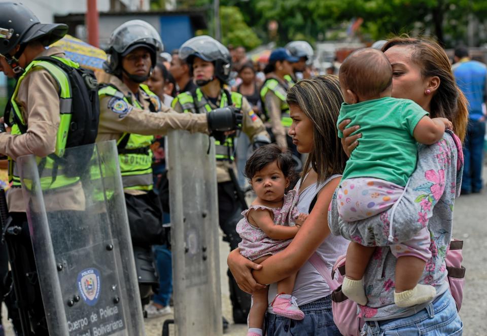 Police keep watch as people line up to buy in a supermarket in the Petare neighborhood in Caracas, on June 1, 2016.  More than 80 percent of basic consumer products including food and medicine are now in short supply in Venezuela, a poll says. / AFP / JUAN BARRETO        (Photo credit should read JUAN BARRETO/AFP/Getty Images)