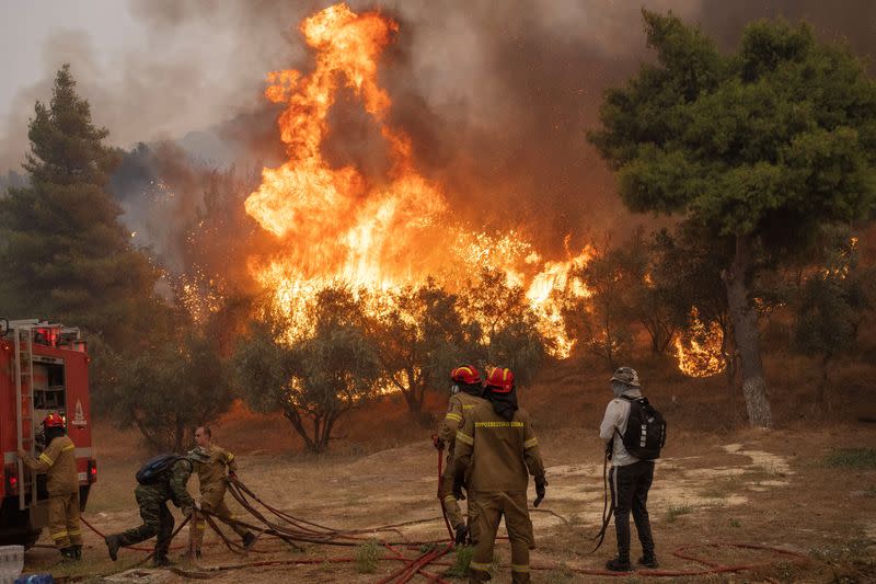 Bomberos y voluntarios intentan atajar un incendio forestal cerca de Atenas