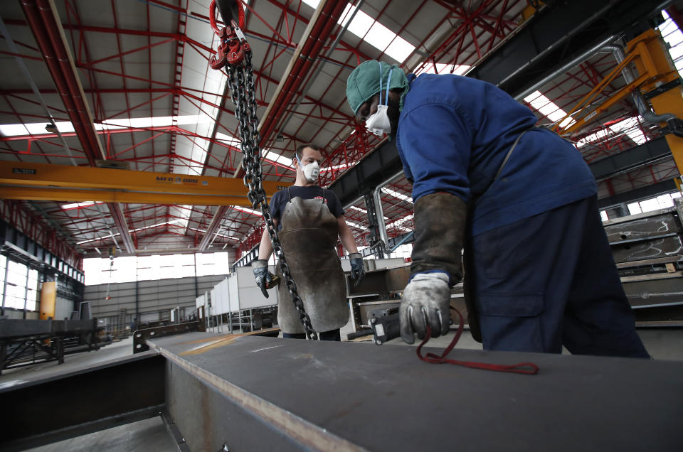 Workers wear face masks at MAP, a factory operating in design, manufacture and installation of steel structures for civil and industrial use, in Corsico, near Milan, Italy, Wednesday, May 6, 2020. Italy began stirring again after the coronavirus shutdown, with 4.4 million Italians able to return to work and restrictions on movement eased in the first European country to lock down in a bid to stem COVID-19 infections. (AP Photo/Antonio Calanni)