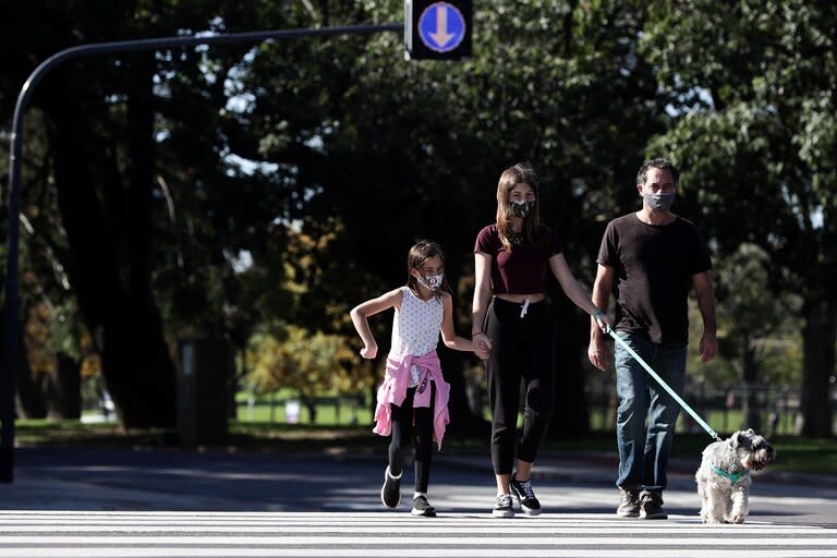 Una familia con barbijo cruza la calle después de que las autoridades permitieron que los niños salgan durante una hora con fines recreativos de acuerdo con el número de identificación de sus padres, en medio del bloqueo impuesto contra la propagación del nuevo coronavirus en Buenos Aires el 16 de m