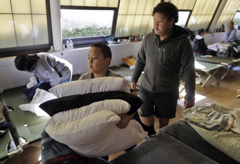 Rylan Moua, left, and his uncle Christopher Vang, right, of Oroville, Calif., gather pillows as they leave a shelter Tuesday, Feb. 14, 2017, in Chico, Calif. (Photo: Marcio Jose Sanchez)