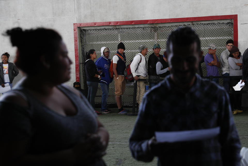 In this Dec. 4, 2018 photo, Central American migrants wait in lines at a job fair, where they are able to apply for Mexican work permits, recover lost Honduran identity documents, and meet with potential employers in Tijuana, Mexico. Once they got their Mexican identification numbers they can meet with recruiters for assembly plants in the area where turnover is often high and jobs are always available. (AP Photo/Rebecca Blackwell)