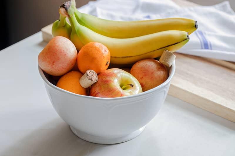 Bowl of fresh fruit with bits of corkscrew.