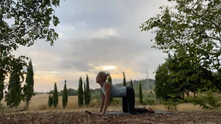 Woman practicing yoga outside stretching her back
