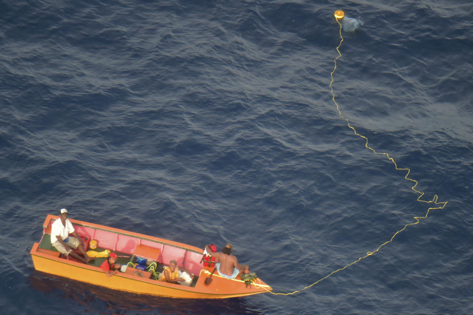 In this image supplied by the Royal New Zealand Air Force (RNZAF), crew wave to a RNZAF Orion near Makin Island in Kiribati, Monday, May 23, 2022. New Zealand's military said Tuesday that an air force plane found seven people who had gone missing. They were aboard two small boats near the remote Pacific nation of Kiribati. (RNZAF via AP)