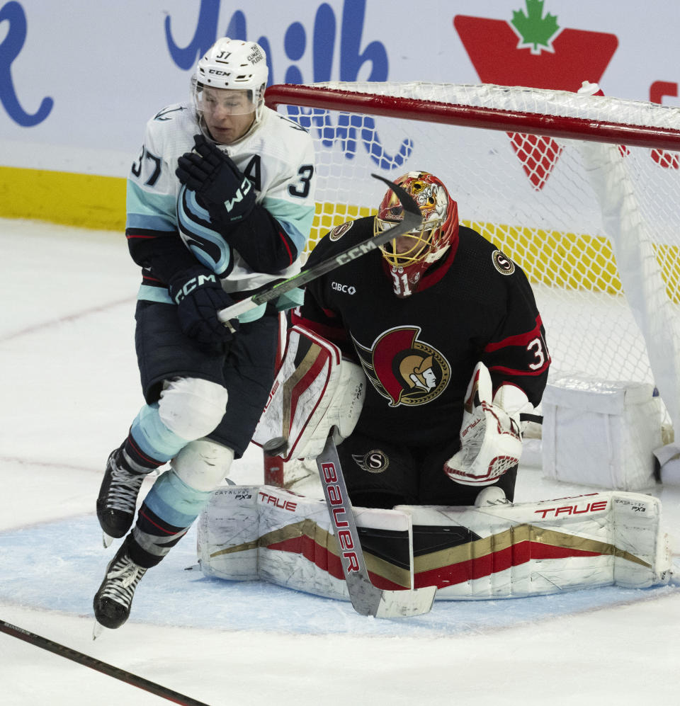 Ottawa Senators goaltender Anton Forsberg, right, makes a save as he is screened by Seattle Kraken centerYanni Gourde, left, during third-period NHL hockey game action, Saturday, Dec. 2, 2023, in Ottawa, Ontario. (Adrian Wyld/The Canadian Press via AP)