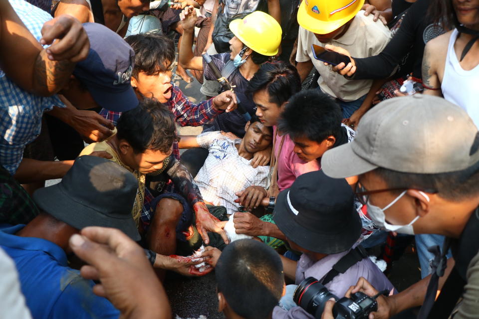 Anti-coup protesters surround an injured man in Hlaing Thar Yartownship in Yangon, Myanmar Sunday, March 14, 2021. A number of people were shot dead during protests in Myanmar's largest city on Sunday, as security forces continued their violent crackdown against dissent following last month's military coup. (AP Photo)