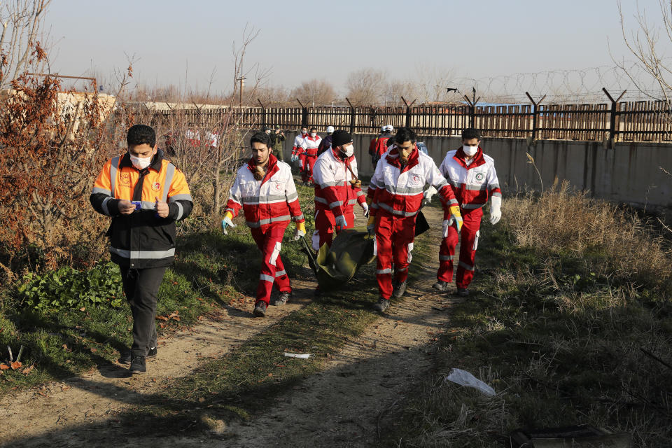 Rescue workers carry the body of a victim of an Ukrainian plane crash in Shahedshahr, southwest of the capital Tehran, Iran, Wednesday, Jan. 8, 2020. A Ukrainian airplane carrying 176 people crashed on Wednesday shortly after takeoff from Tehran's main airport, killing all onboard. (AP Photo/Ebrahim Noroozi)