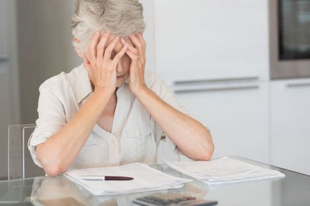 Worried senior woman paying her bills