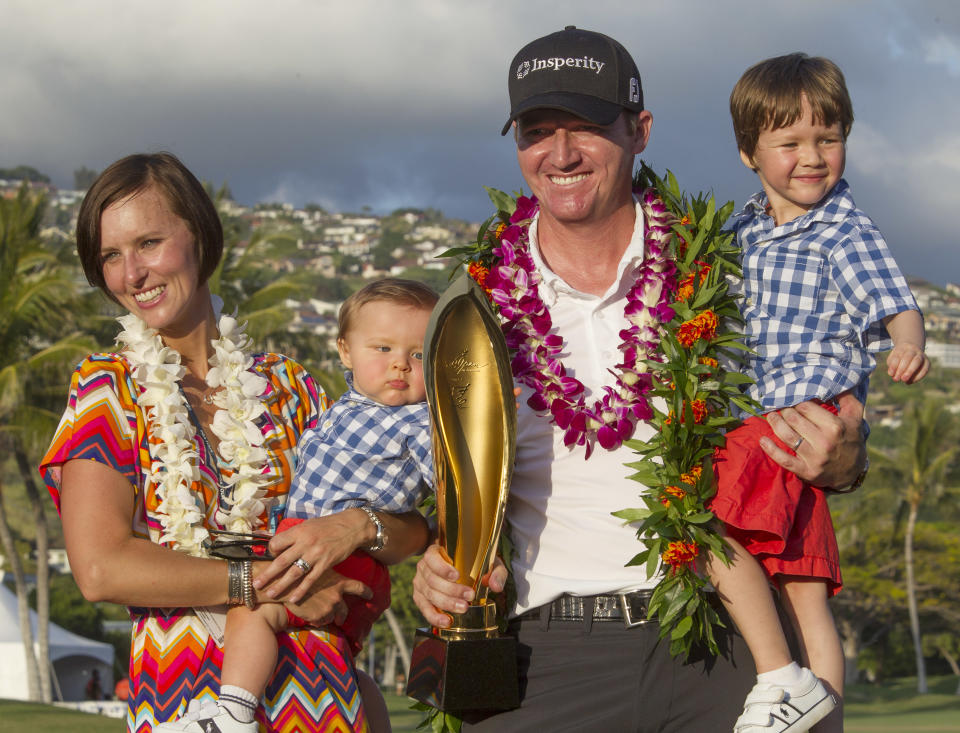 Jimmy Walker, second from right, holds his son Mclain, right, as his wife Erin Walker, left, holds their son Beckett, while they pose for pictures with the Sony Open Trophy after Jimmy won the golf tournament at Waialae Country Club, Sunday, Jan. 12, 2014, in Honolulu. (AP Photo/Eugene Tanner)
