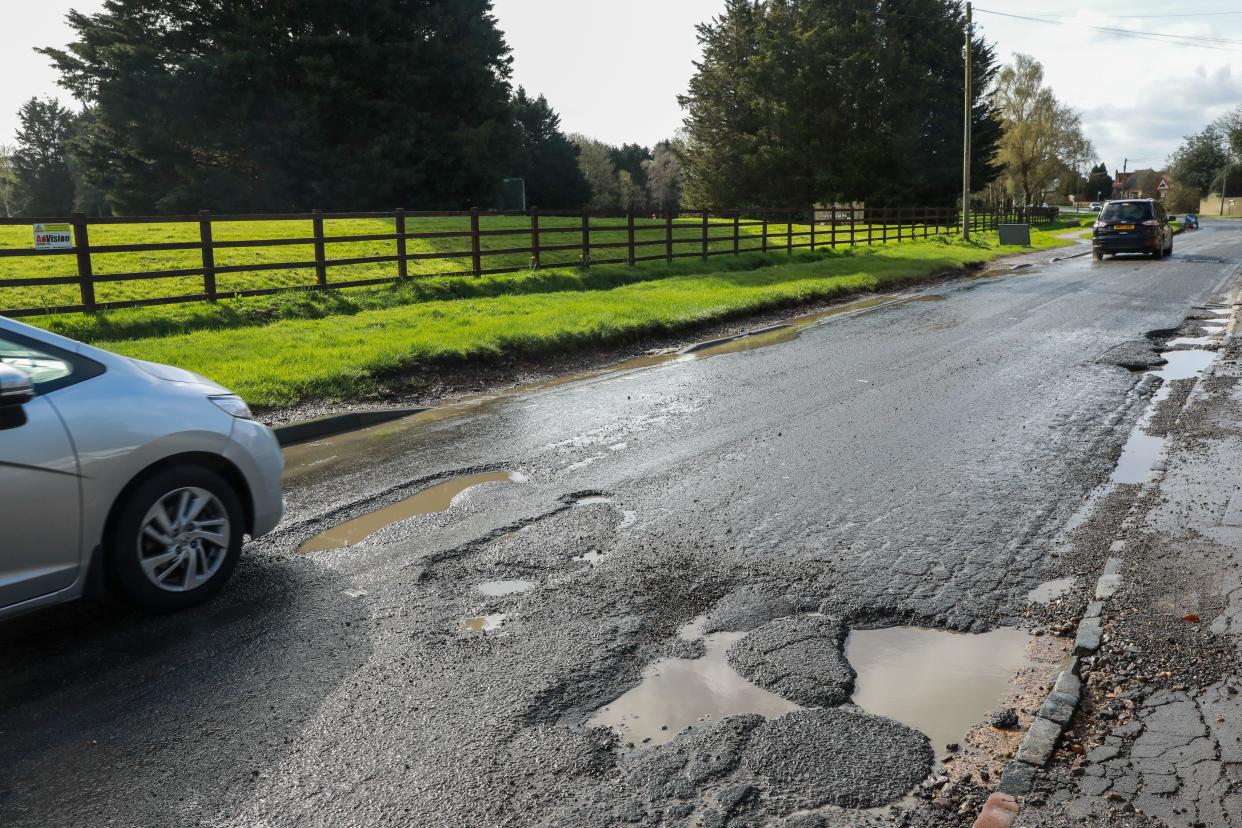 South Bucks, UK. 11th April, 2023. A vehicle passes large potholes in a road. The Asphalt Industry Alliance recently reported that 18% of the local roads network is considered to be in poor condition with less than five years of life remaining. Holes in roads can damage vehicles and endanger all types of road users. Credit: Mark Kerrison/Alamy Live News