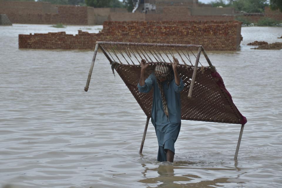 A man carries cot after he salvaged it from his flood-hit home in Jaffarabad, a district of Pakistan's southwestern Baluchistan province, Thursday, Aug. 25, 2022. Pakistan's government in an overnight appeal sought relief assistance from the international community for flood-affected people in this impoverished Islamic nation, as the exceptionally heavier monsoon rain in recent decades continued lashing various parts of the country. (AP Photo/Zahid Hussain)
