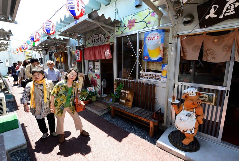 People stroll at the Ofunato Yatai Mura, an area devastated by a tsunami in 2011, in Ofunato, Japan, on July 20, 2013. Tourists want to see the devastation and the monuments to those who died, the latest example of a phenomenon dubbed "dark tourism" where holidaymakers pay to witness the aftermath of others' misery