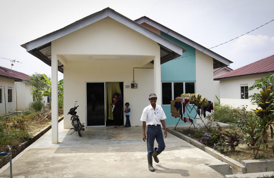 In this photo taken on Oct. 4, 2012, Faizal Zulkifli leaves his house after lunch at a rural community in Pulau Manis village, Pahang state, Malaysia, Thursday, Nov. 8, 2012. Faizal Zulkifli, a father of three, is one of villagers living for free in low-cost bungalows and working on a high-tech hydroponic farm, a setup the Malaysian technology firm Iris Corp. hopes to replicate elsewhere. The government is now involved in a plan to build similar villages across this Southeast Asian country, where nearly one of 10 people in rural provinces lives below the official poverty line. (AP Photo/Vincent Thian)