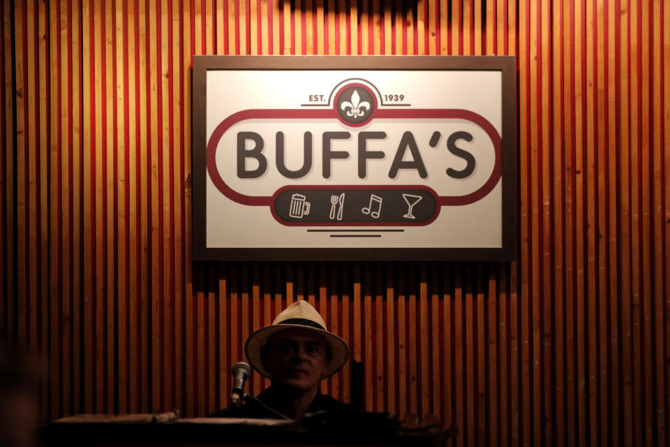 Pianist Harry Mayronne plays during a livestream gig with singer Leslie Cooper and her son Doyle Cooper, inside an empty and closed Back Room at Buffa's in New Orleans, Tuesday, April 28, 2020. With New Orleans music venues shuttered for more than a month now because of the coronavirus outbreak, musicians and fans are finding new places to connect – porches, living rooms, studios and lawns – and reaching their largest audiences online, many streaming performances live on social media platforms. But for the city's club owners awaiting the green light to reopen there's concern about all the uncertainties, like how long it may take tourists to return, how soon the music scene will rebound and when it does, what it will look like. (AP Photo/Gerald Herbert)