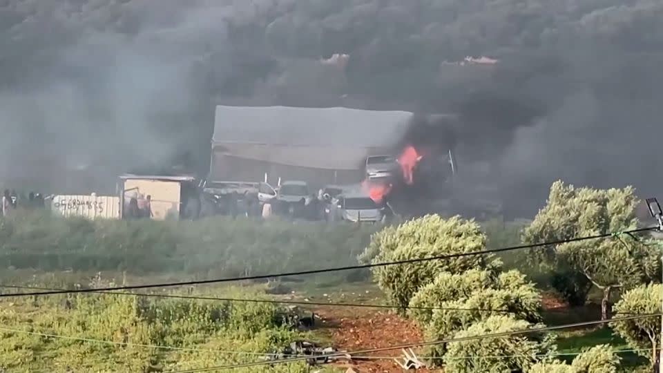 Israeli settlers wearing headscarves are seen near billowing smoke. - Reuters