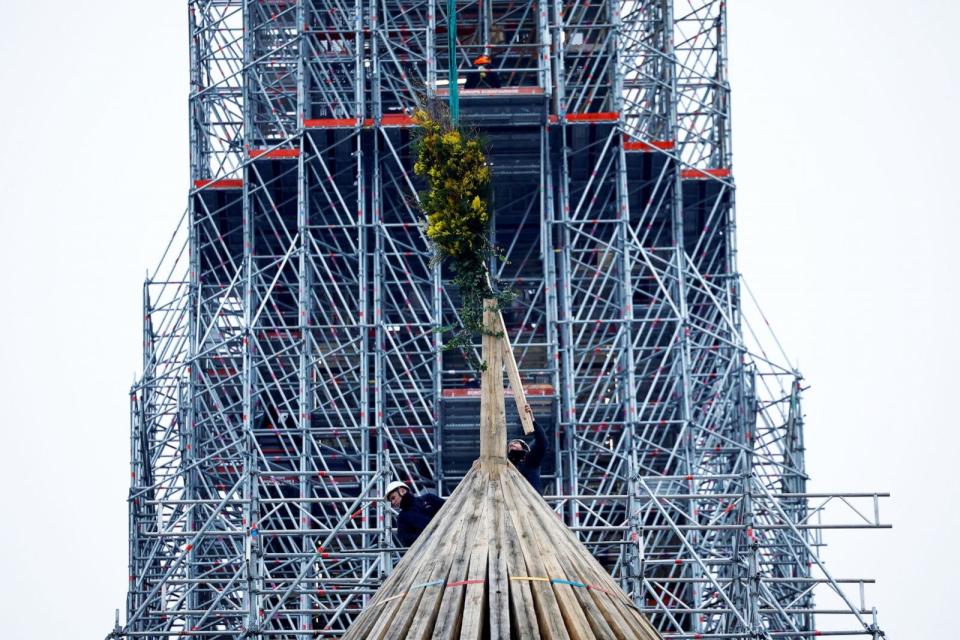 PHOTO: Carpenters install the traditional bouquet of flowers to celebrate the end of the reconstruction of the medieval choir framework of the Notre-Dame de Paris Cathedral, in Paris, on Jan. 12, 2024.  (Sarah Meyssonnier/Reuters, FILE)