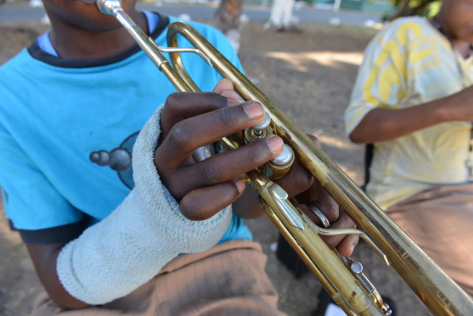 In this Feb, 13, 2014 photo, the bandaged hand of 15-year-old Chevon Harriott is shown fingering valves on a trumpet while he practices under the shady canopy of trees that dot the campus of the Alpha Boys’ School school in Kingston, Jamiaca. Decade after decade, Alpha alumni have emerged from the musical hothouse in Kingston to bring the sounds of Jamaican ska, rocksteady and reggae to the world. Alpha’s music program dates back to 1892, when boys participated in a drum and fife corps. (AP Photo/David McFadden)