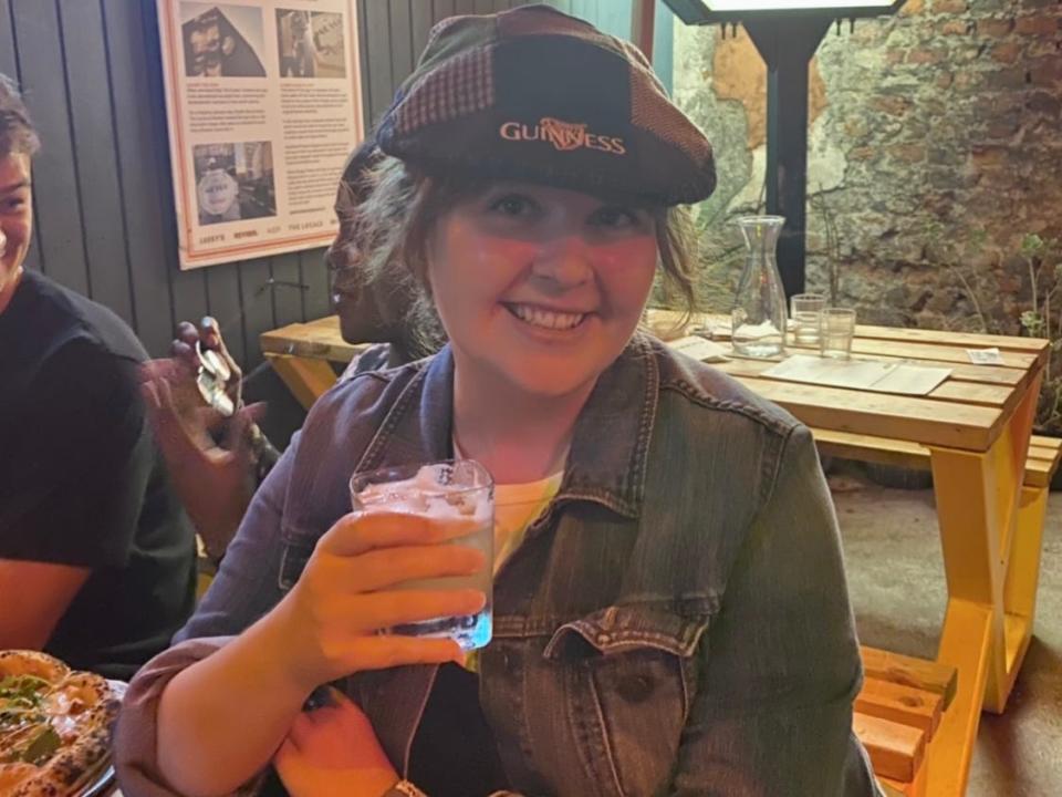 alexis wearing an irish cap and drinking beer in a pub in ireland