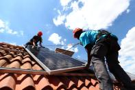 Kauahou and Navarro, workers of the installation company Alromar, set up solar panels on the roof of a home in Colmenar Viejo