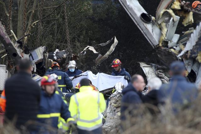 Firefighters collect a body after a collision in Tempe, about 376 kilometres (235 miles) north of Athens, near Larissa city, Greece, Wednesday, March 1, 2023. A passenger train carrying hundreds of people, including many university students returning home from holiday, collided before midnight Tuesday at high speed with an oncoming freight train. (AP Photo/Giannis Papanikos)
