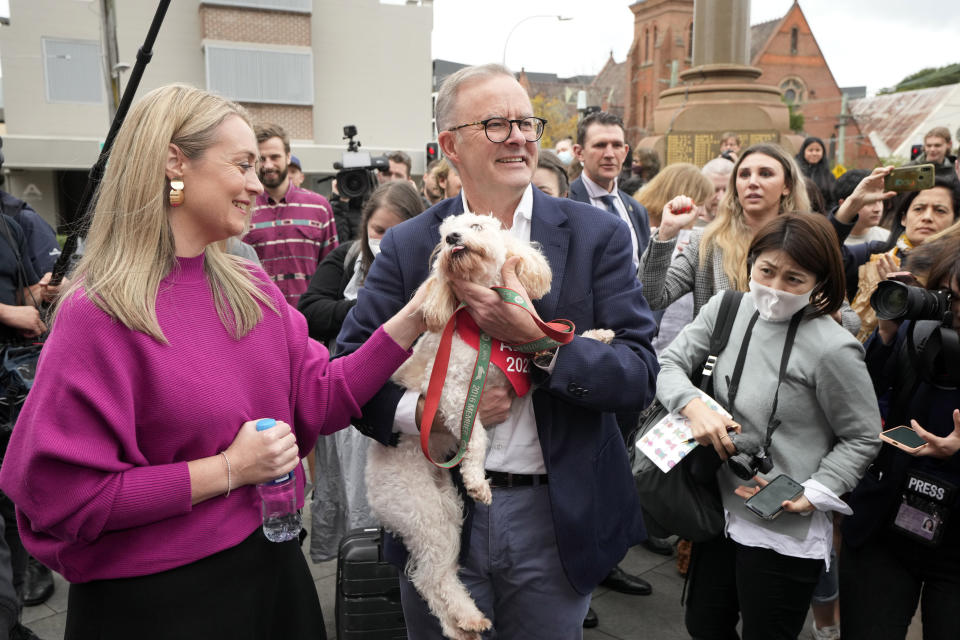 Labor Party leader Anthony Albanese holds his dog, Toto, after he and his partner Jodie Haydon, left, voted in Sydney, Australia, Saturday, May 21, 2022. Australians go to the polls following a six-week election campaign that has focused on pandemic-fueled inflation, climate change and fears of a Chinese military outpost being established less than 1,200 miles off Australia's shore. (AP Photo/Rick Rycroft)