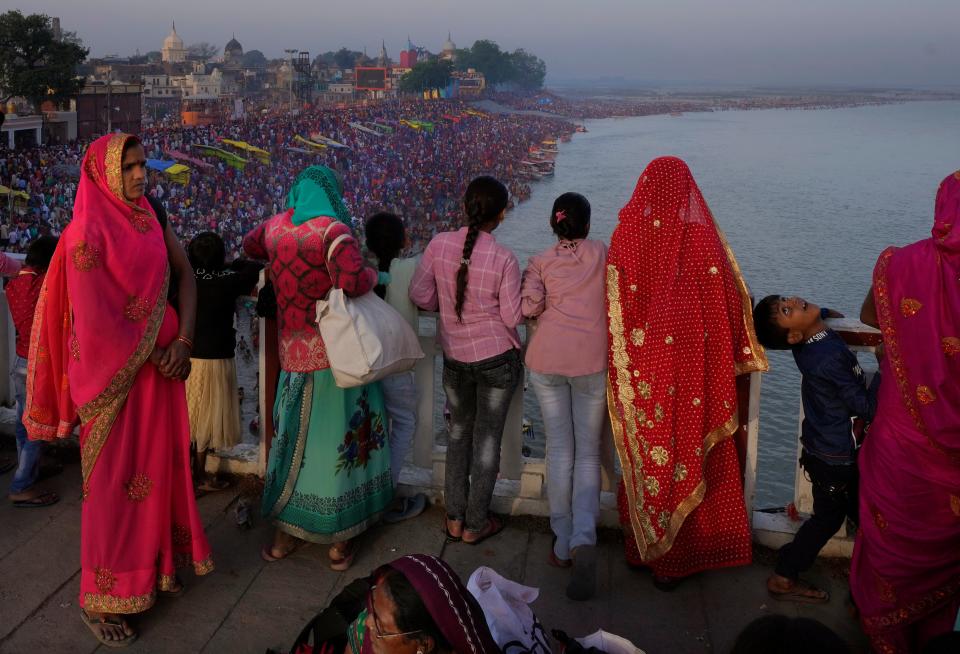 Families watch from a bridge as thousands of people enter the holy River Saryu in Ayodhya, India, Thursday, March 30, 2023. The United Nations says India will be the world’s most populous country by the end of April, eclipsing an aging China. (AP Photo/Manish Swarup)