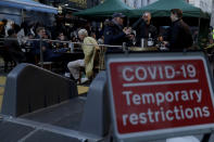 People sit at outdoor tables setup today for drinks to be served in the Soho area of central London, on the day some of England's third coronavirus lockdown restrictions were eased by the British government, Monday, April 12, 2021. People across England can get their hair cut, eat and drink outside at restaurants and browse for clothes, books and other "non-essential" items as shops and gyms reopened Monday after months of lockdown. (AP Photo/Matt Dunham)