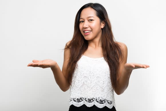 A millennial woman shrugging her shoulders and hands.