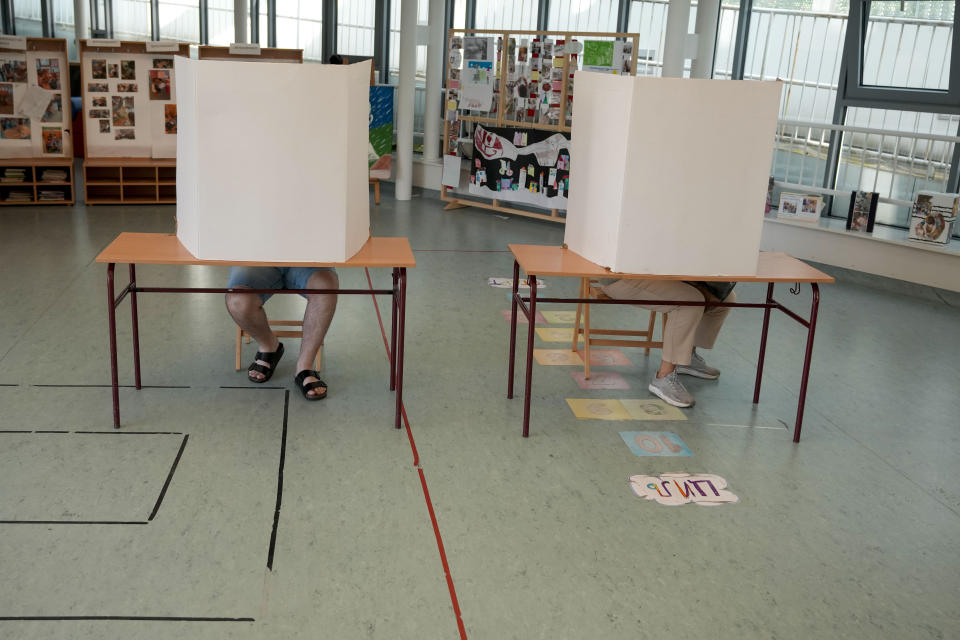 Voters prepare ballots for the local election at a polling station in Belgrade, Serbia, Sunday, June 2, 2024. Voters in Serbia on Sunday are casting ballots in a rerun election in the capital, Belgrade, and in dozens of other cities and towns, with ruling right-wing populists seeking to cement their already vast hold on power. The vote in Belgrade is being repeated after reports of widespread irregularities last December triggered political tensions and accusations that President Aleksandar Vucic's Serbian Progressive Party rigged the vote. (AP Photo/Darko Vojinovic)