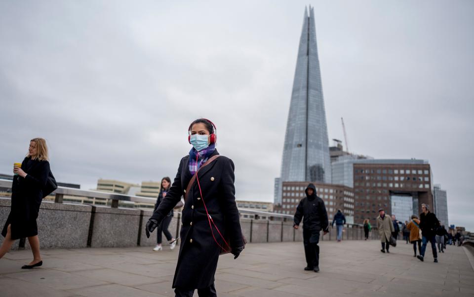 A commuter wears a mask whilst walking across a quiet London Bridge into the City of London during the morning rush hour on March 18, 2020 as people take precautions amid the coronavirus outbreak. - The British government will on Wednesday unveil a raft of emergency powers to deal with the coronavirus epidemic, including proposals allowing police to detain potentially infected people to be tested. (Photo by Tolga AKMEN / AFP) (Photo by TOLGA AKMEN/AFP via Getty Images)