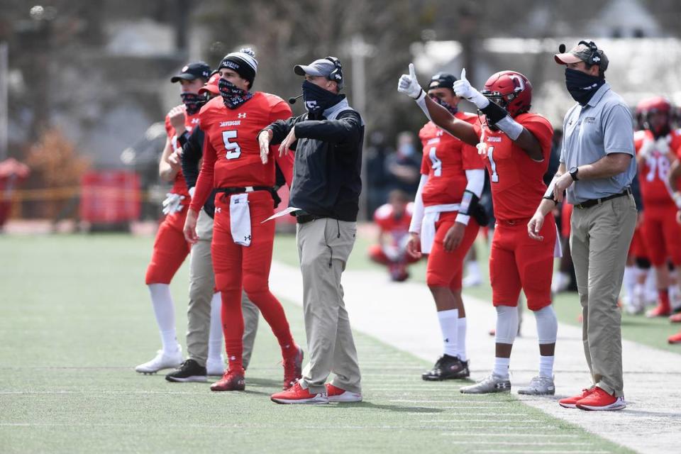 Davidson coach Scott Abell (center, in black) signals to his team during a game against Presbyterian in March. Abell and his staff have turned the program around since arriving in 2018, in part by relying on a spread option, run-heavy offense.