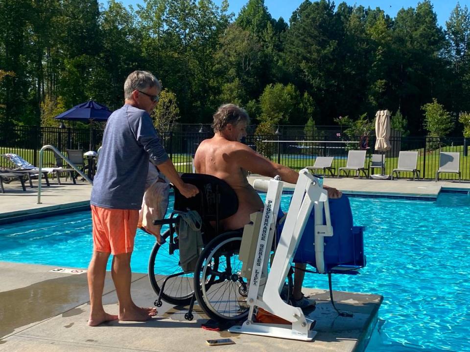 Rob Paxton assists Ed Petner on the way to the Clayton pool where they swim and Petner hopes to raise money for the Christopher Reeve Foundation.