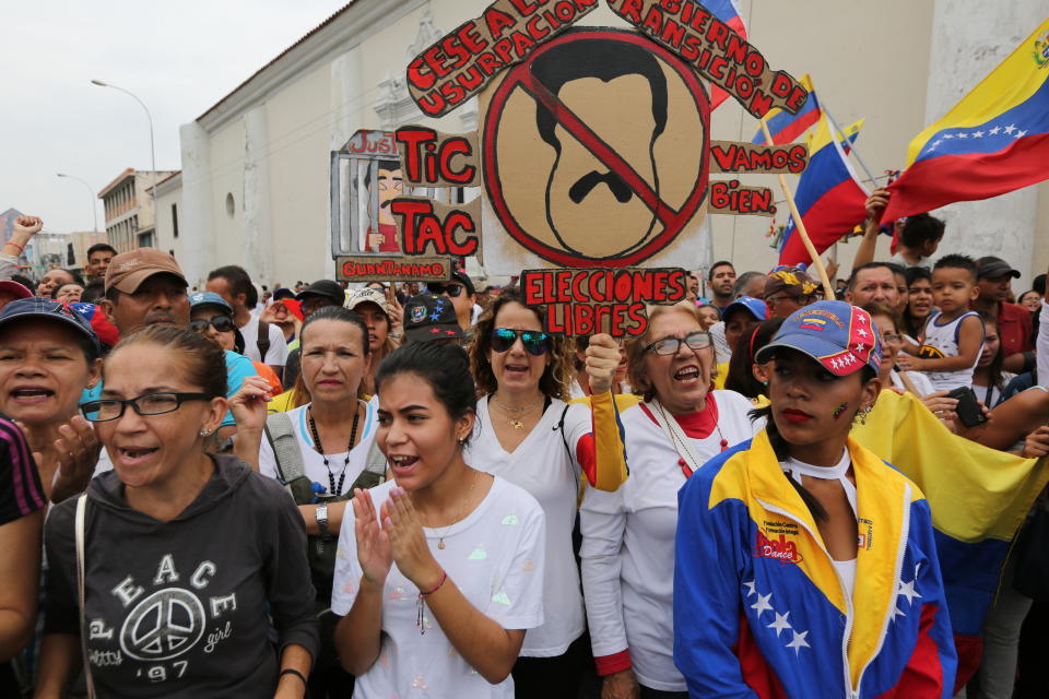Supporters of Venezuela's opposition leader and self proclaimed president Juan Guaido, hold sign against President Nicolas Maduro as they cheer during a rally in Maracay, Venezuela, Friday, April 26, 2019. The Trump administration has added Venezuelan Foreign Minister Jorge Arreaza to a Treasury Department sanctions target list as it increases pressure on Guaido's opponent, embattled President Nicolas Maduro. (AP Photo/Fernando Llano)