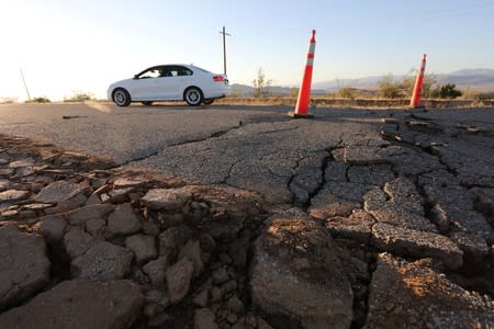 A car passes over a fissure that opened on a highway during a powerful earthquake that struck Southern California, near the city of Ridgecrest