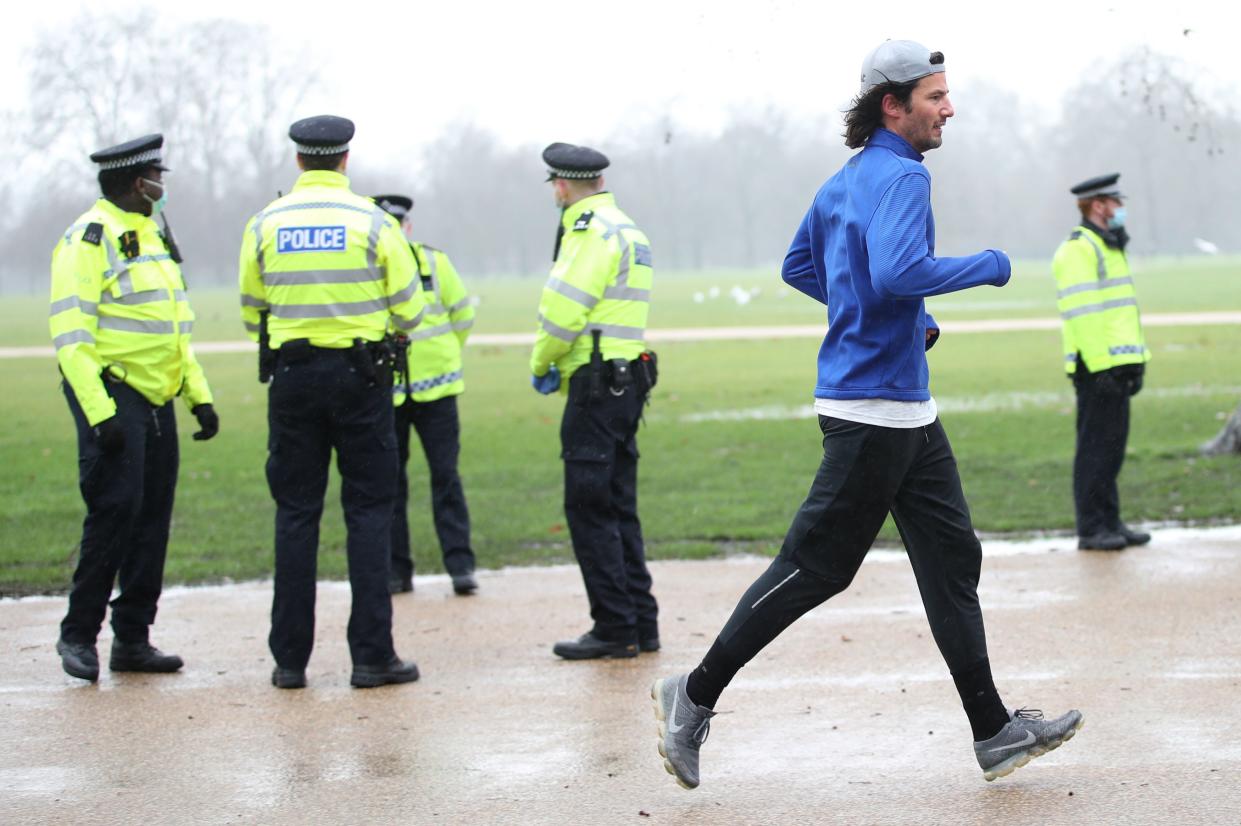 A man jogging past police officers in London’s Hyde Park (PA)